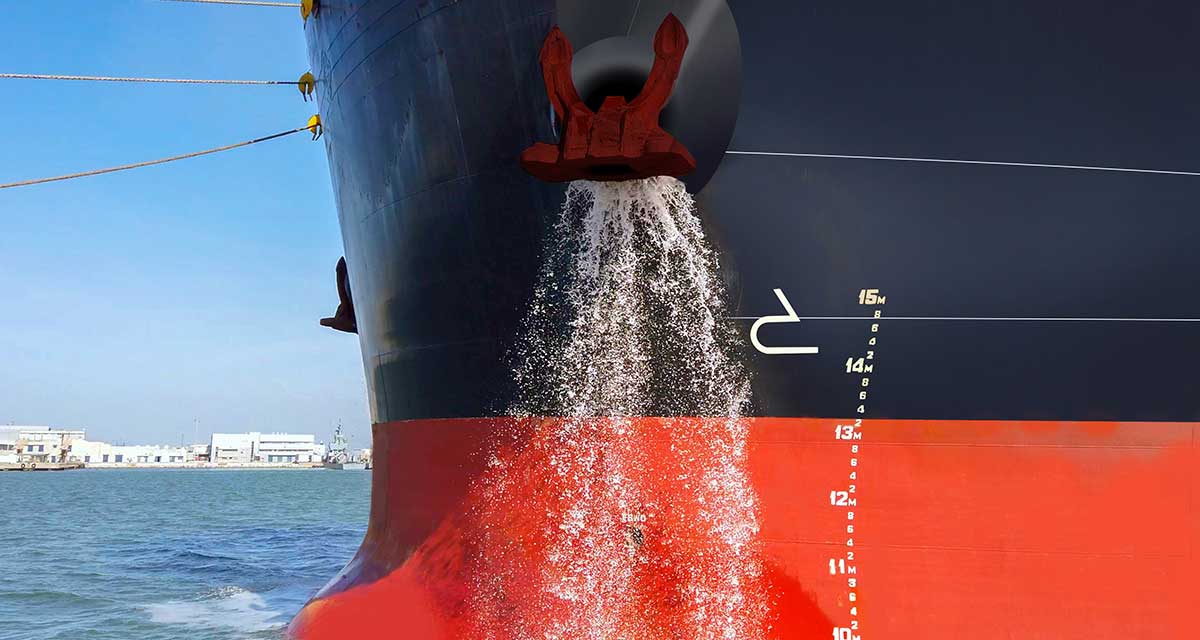Close-up image of a ship releasing ballast water through a side outlet while docked in port