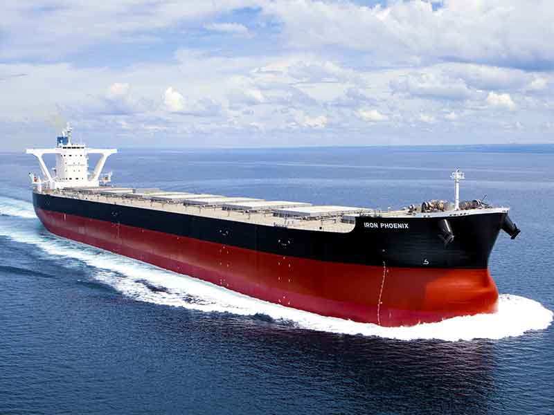 The bulk carrier ship “Iron Phoenix” sails at sea, showcasing its sleek black and red hull while promoting sustainable marine biofuel usage