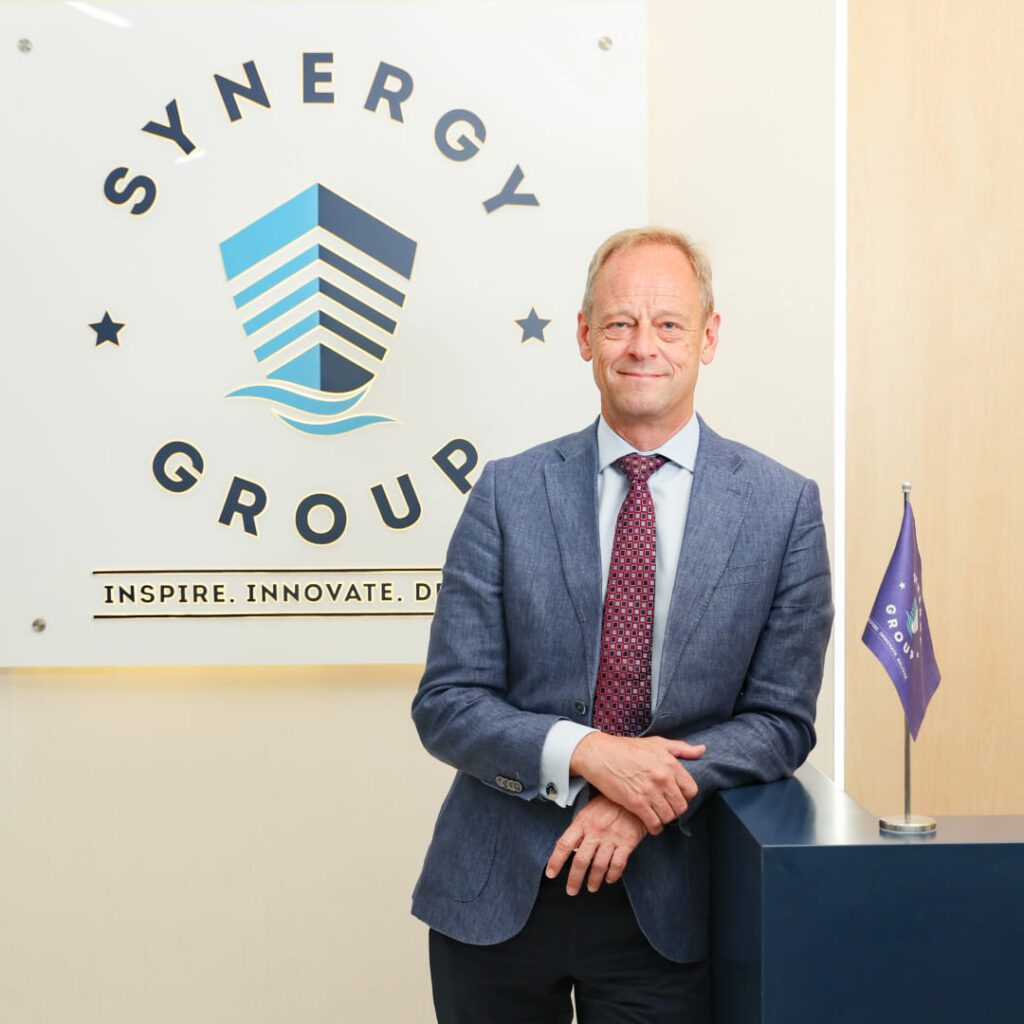 Jesper Kristensen, Group CEO of Synergy Marine Group, photographed in front of a wall featuring the company logo.