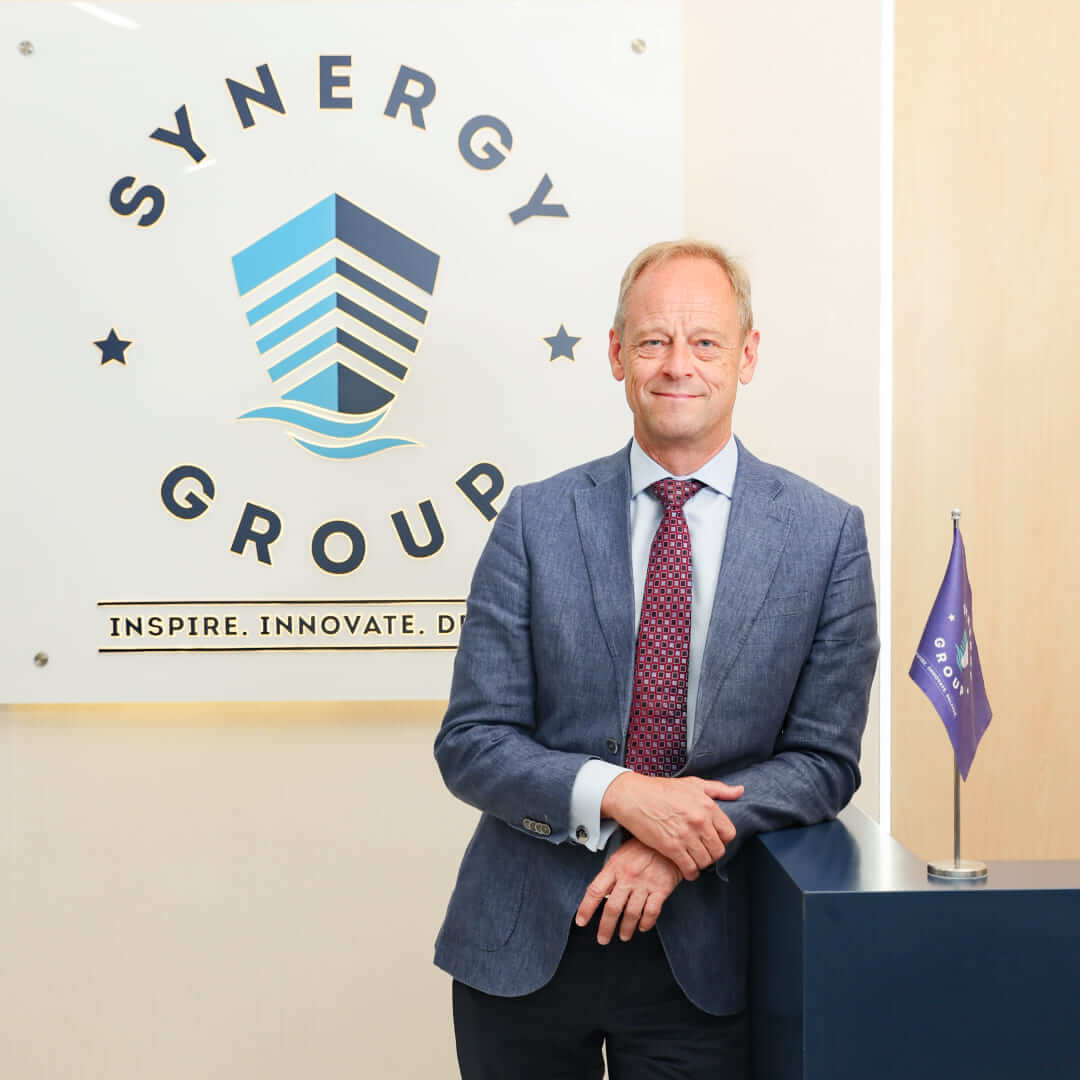Jesper Kristensen, Group CEO of Synergy Marine Group, photographed in front of a wall featuring the company logo.