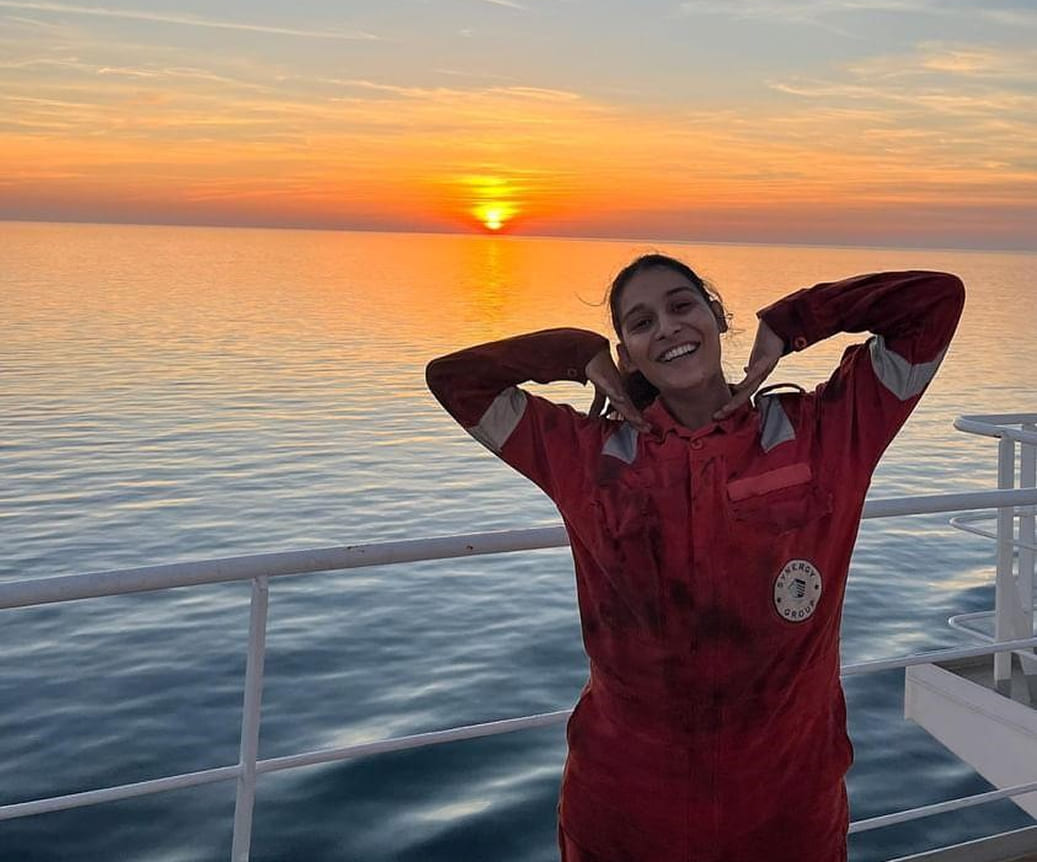 Engine Cadet Anushka Rudola smiling on deck in front of a sunset