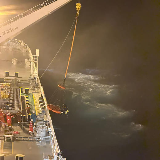 Close-up view of the personnel-transfer basket and sailing vessel being secured during the rescue operation next to KUFRA.