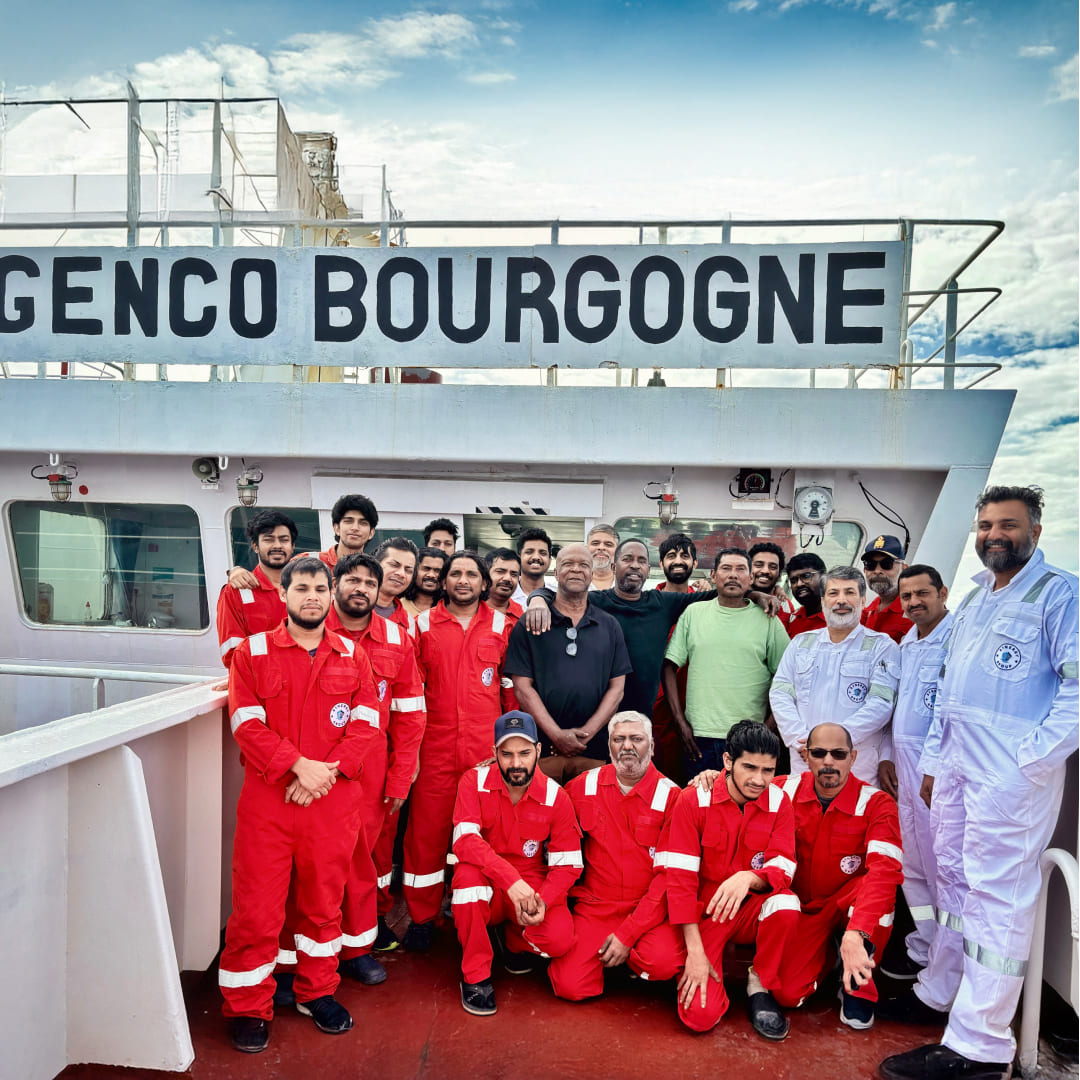 Synergy crew in boiler suits posing on the deck of the Genco Bourgogne with the rescued individuals.
