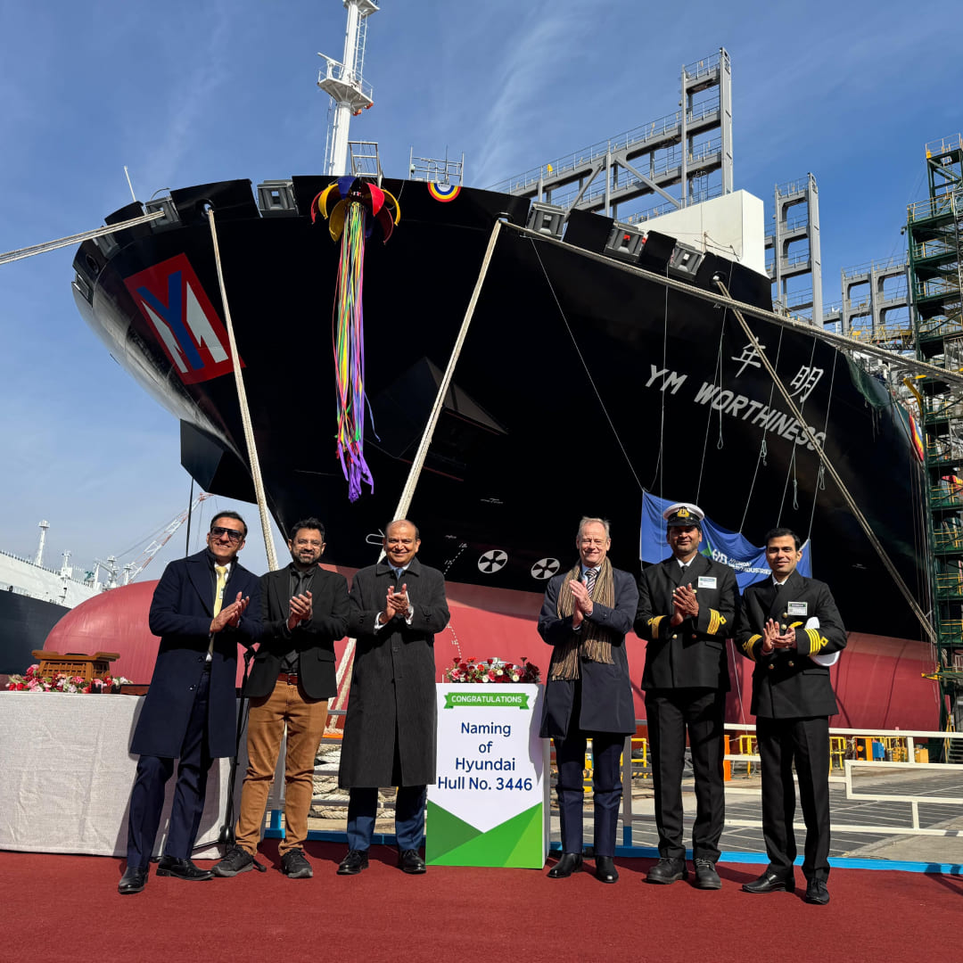 Synergy leadership and ship crew in formal uniforms and safety gear posing on the deck of the YM Willpower.